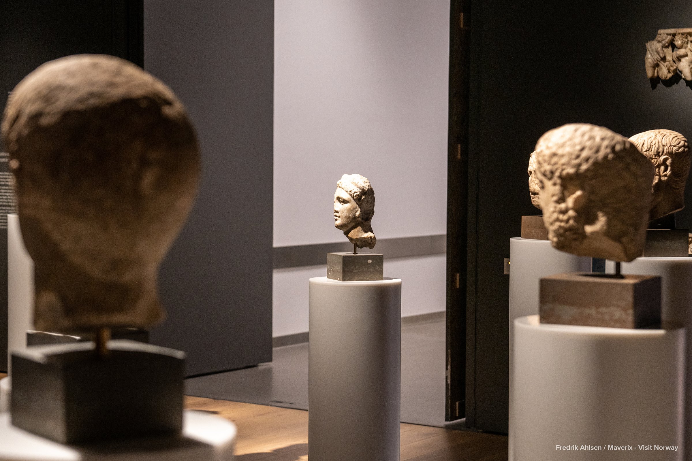 Stone busts on pedestals in a dimly lit gallery at the National Museum of Norway.