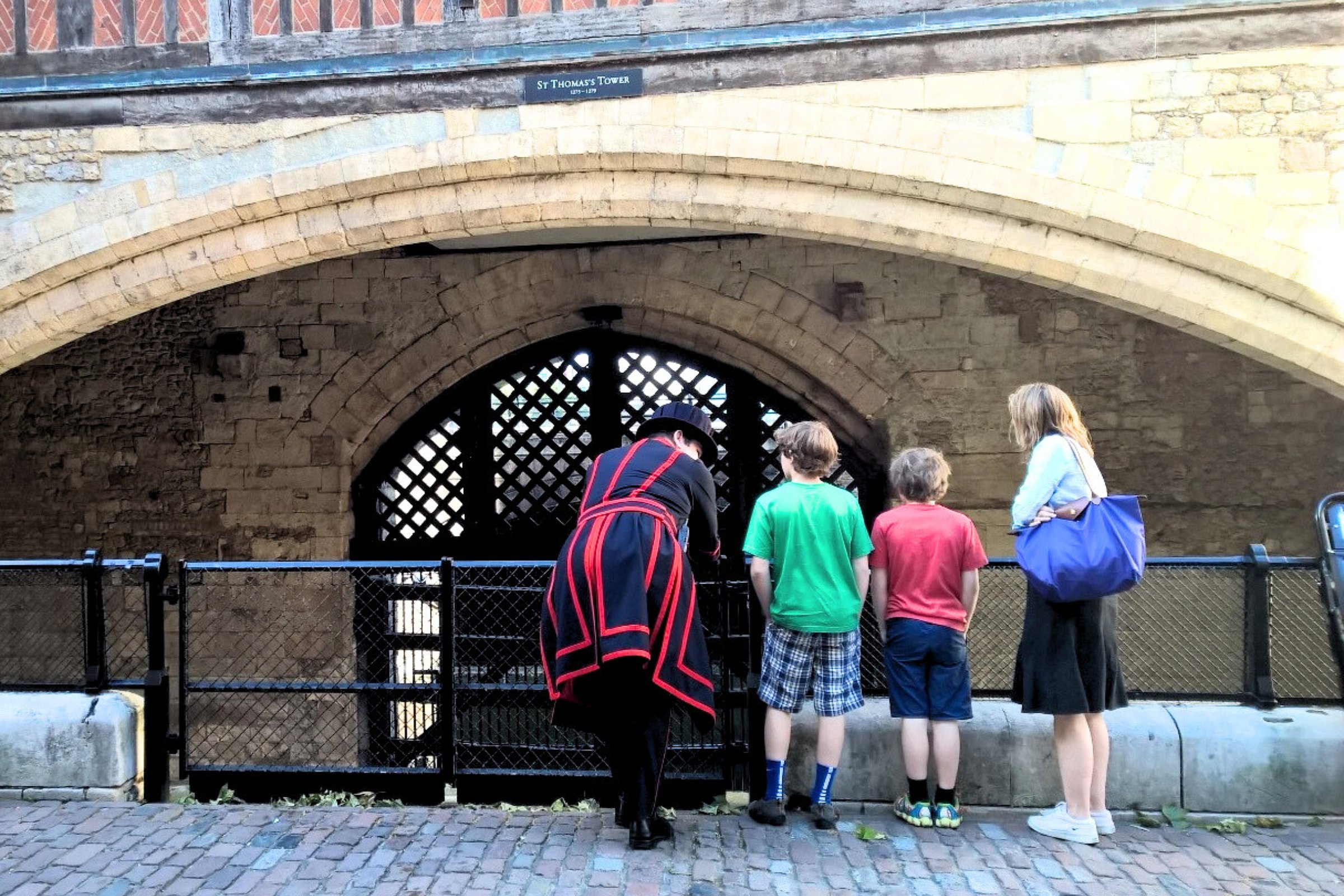 Beefeater guide speaking with a family of three in front of Traitor’s Gate at the Tower of London, under the arch of St Thomas’s Tower.