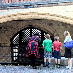Beefeater guide speaking with a family of three in front of Traitor’s Gate at the Tower of London, under the arch of St Thomas’s Tower.