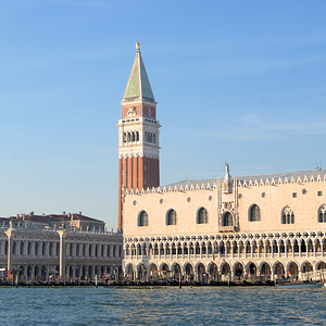 Panoramic view of the Doge's Palace and Campanile di San Marco from the water, showcasing Venice’s iconic architecture against a clear blue sky.