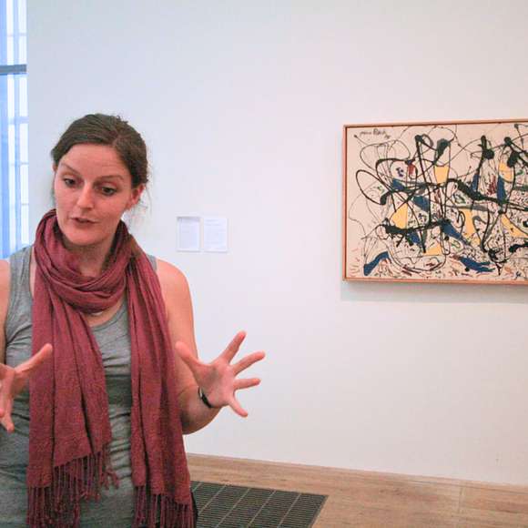 Art guide passionately explaining a Jackson Pollock painting to visitors inside Tate Modern.