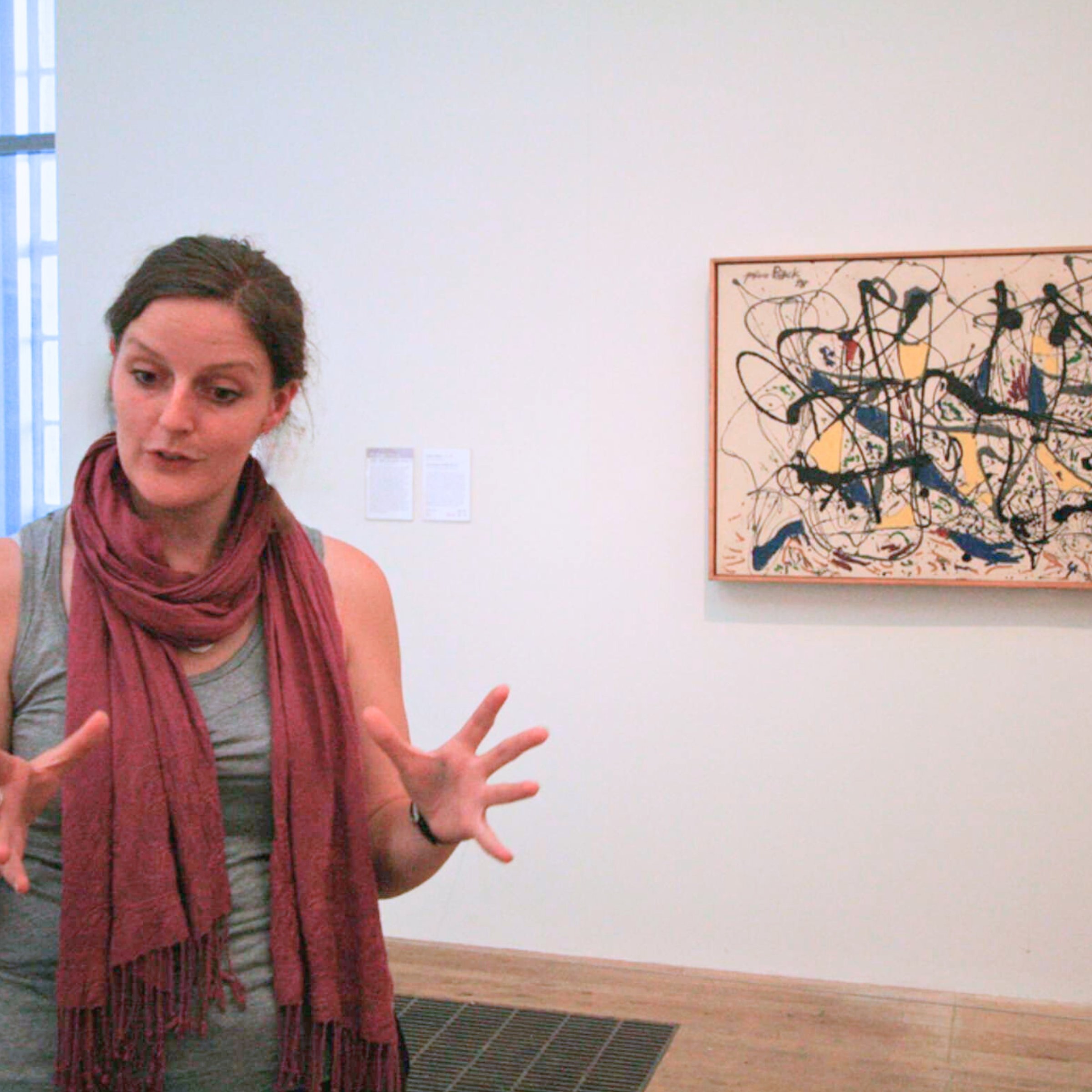 Art guide passionately explaining a Jackson Pollock painting to visitors inside Tate Modern.